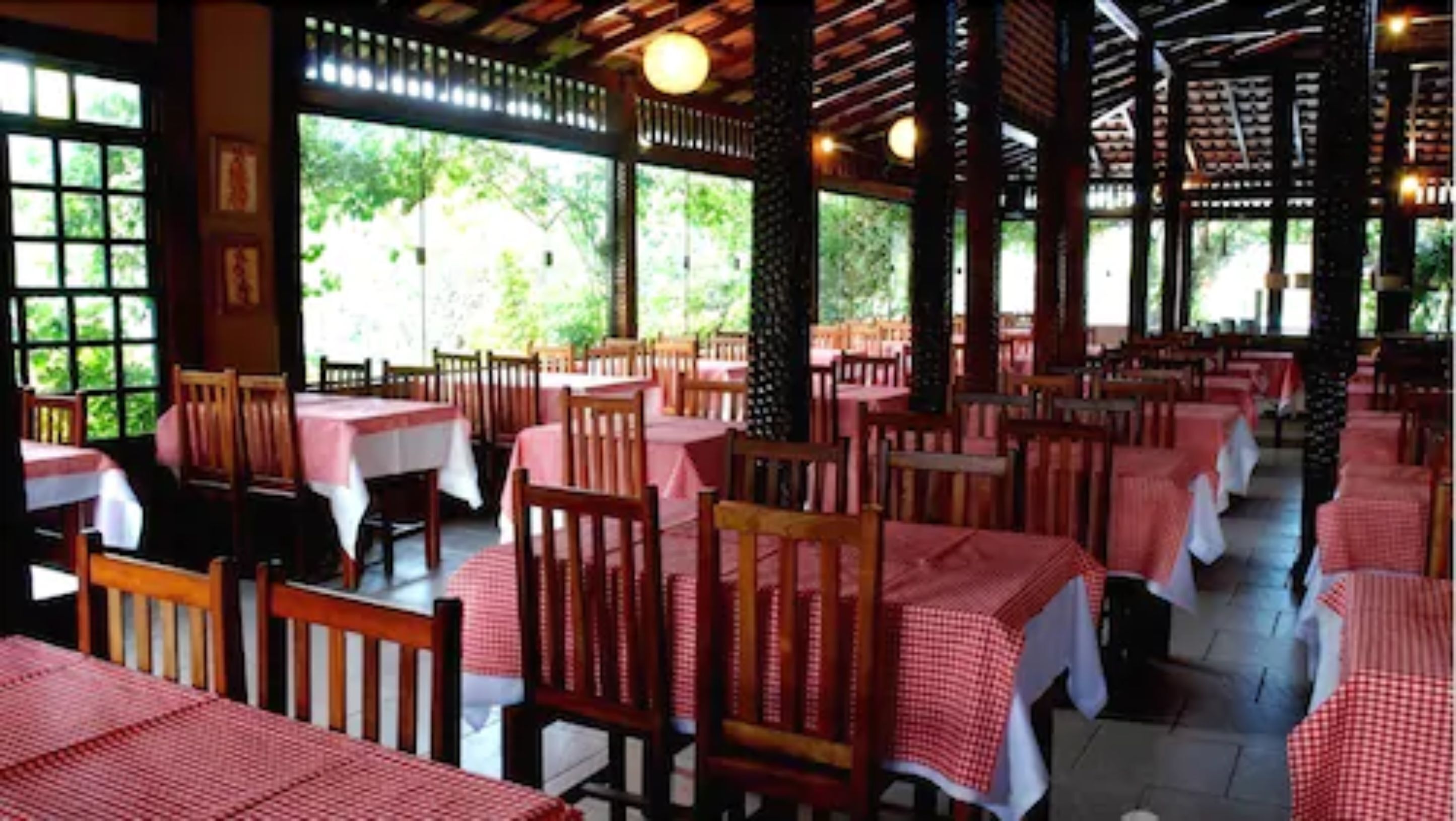 Un restaurant avec des tables et des chaises en bois, recouvertes de nappes à carreaux rouges et blancs.