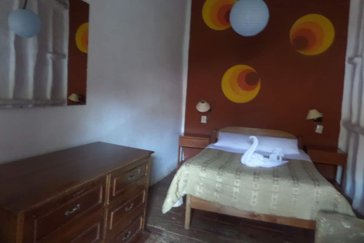 Ein Schlafzimmer mit einem hölzernen Schminktisch, einem Bett mit einer Zierenschwan-Kissen und einer Wand mit kreisförmigen Mustern.