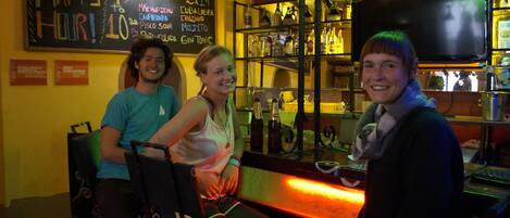 A bar area with a chalkboard menu, shelves with bottles, and a neon sign.