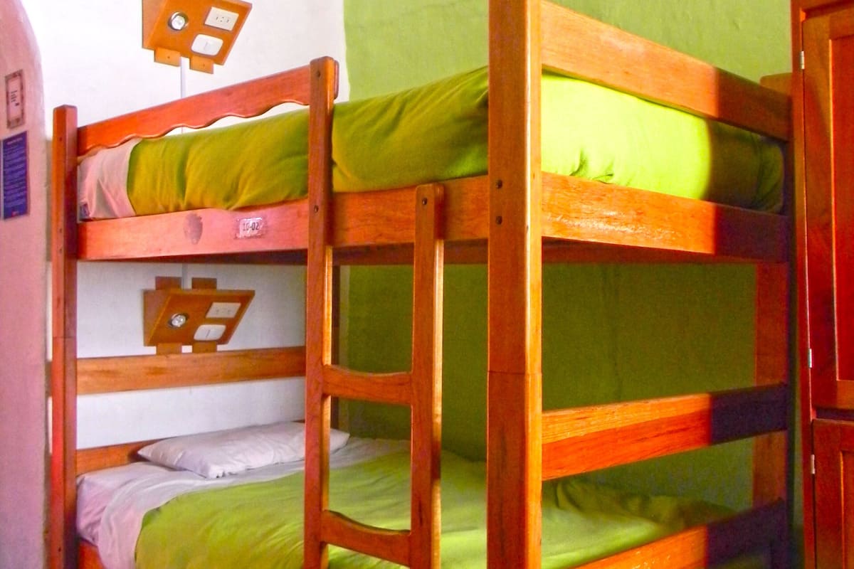 Ein Schlafzimmer mit Etagenbett, grüner Bettwäsche und einem Holtzrahmen.