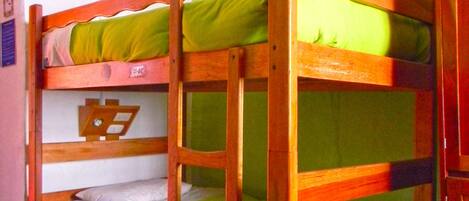 A bunk bed room with green bedding and a wooden frame.