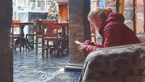 Un espace intérieur doté d’un sol en pierre, de meubles en bois et d’une personne utilisant un appareil mobile.