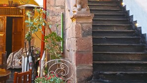 Un escalier menant à une porte ornée d’une pancarte « Bonne année 2019 », d’une enseigne rouge indiquant « Pirwa Hostels Colonial » et d’une statue de lion.