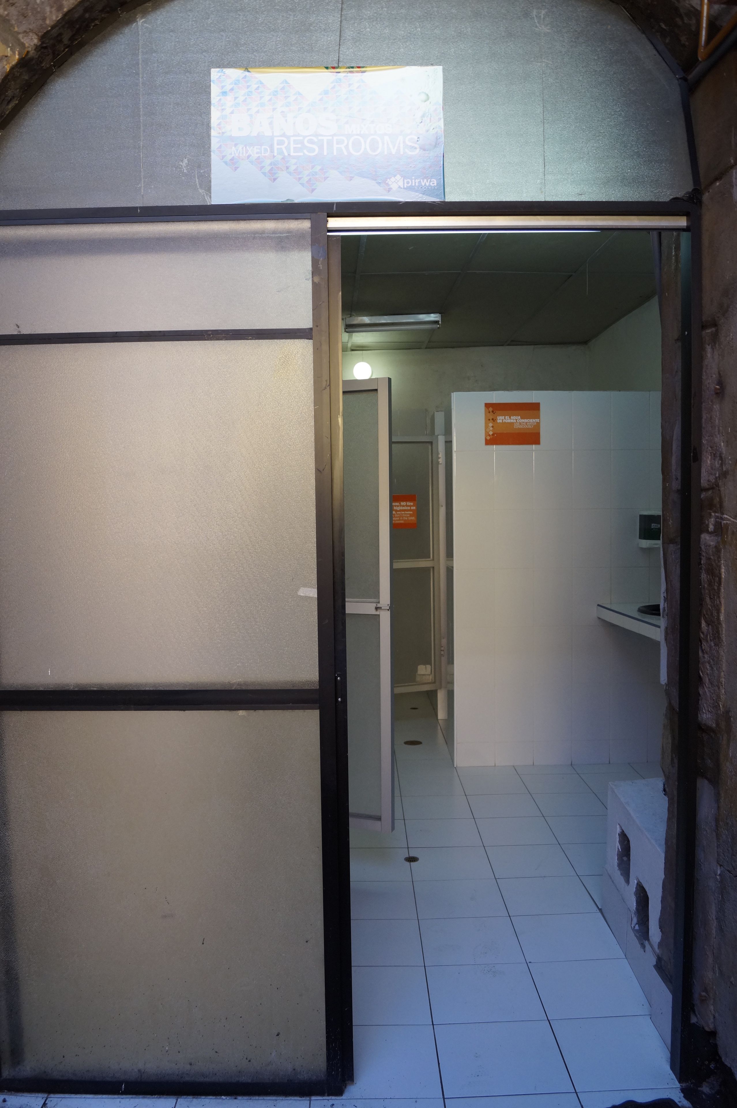 A corridor with a sign indicating mixed restrooms.