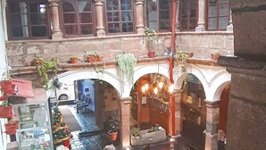 L’intérieur d’un hôtel avec un escalier central, de nombreuses arcades et un sapin de Noël.