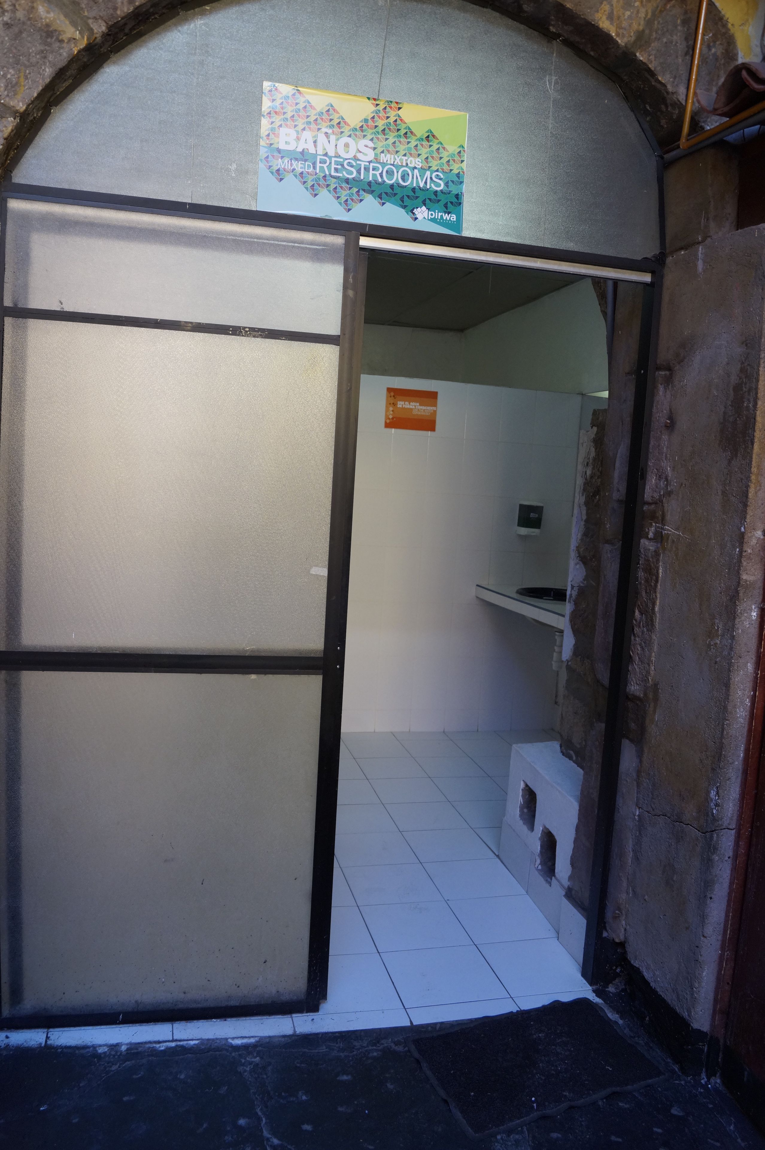 Une entrée de toilettes avec une pancarte indiquant : « TOILETTES MIXTES ».
