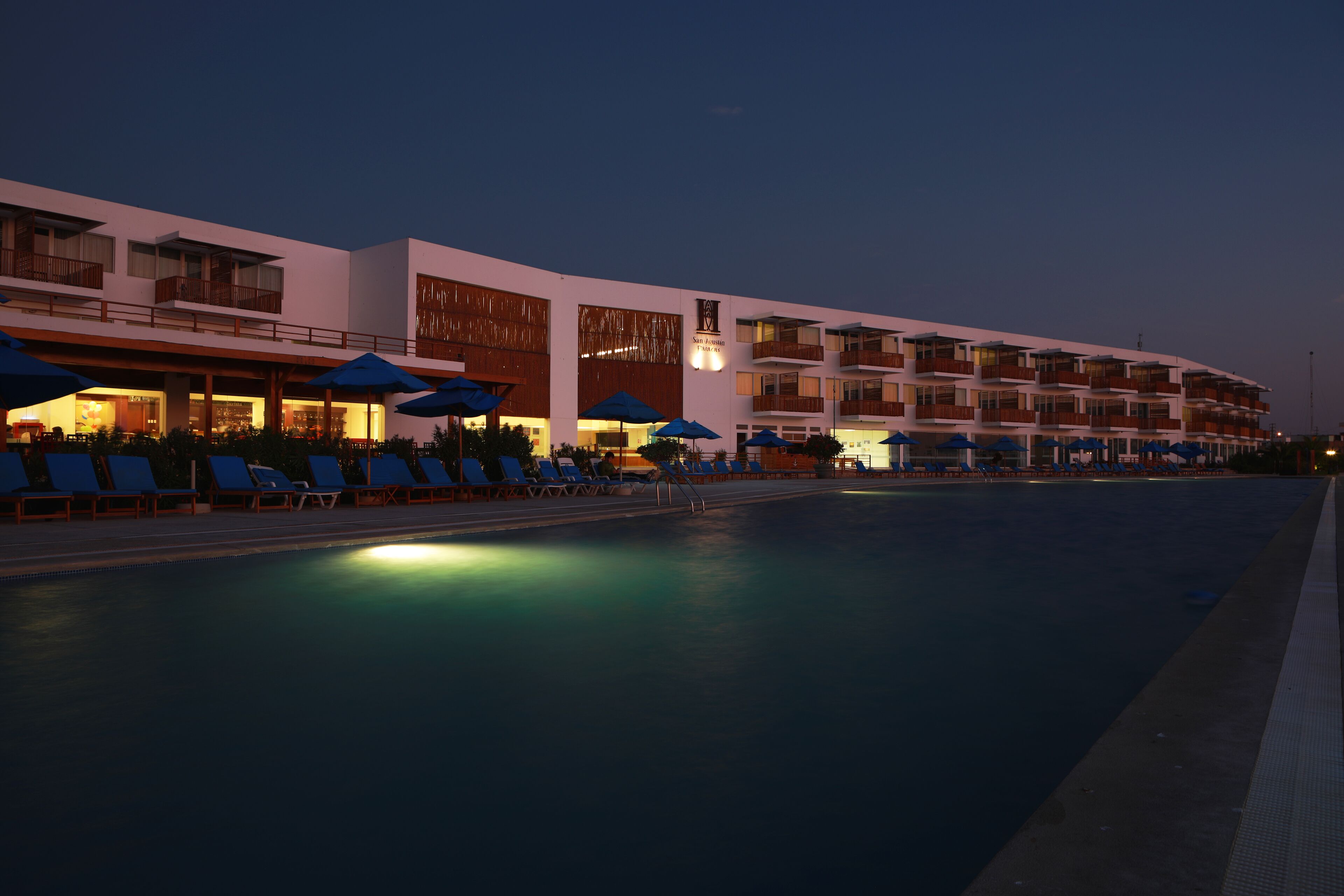 Un hotel con piscina, tumbonas y sombrillas.