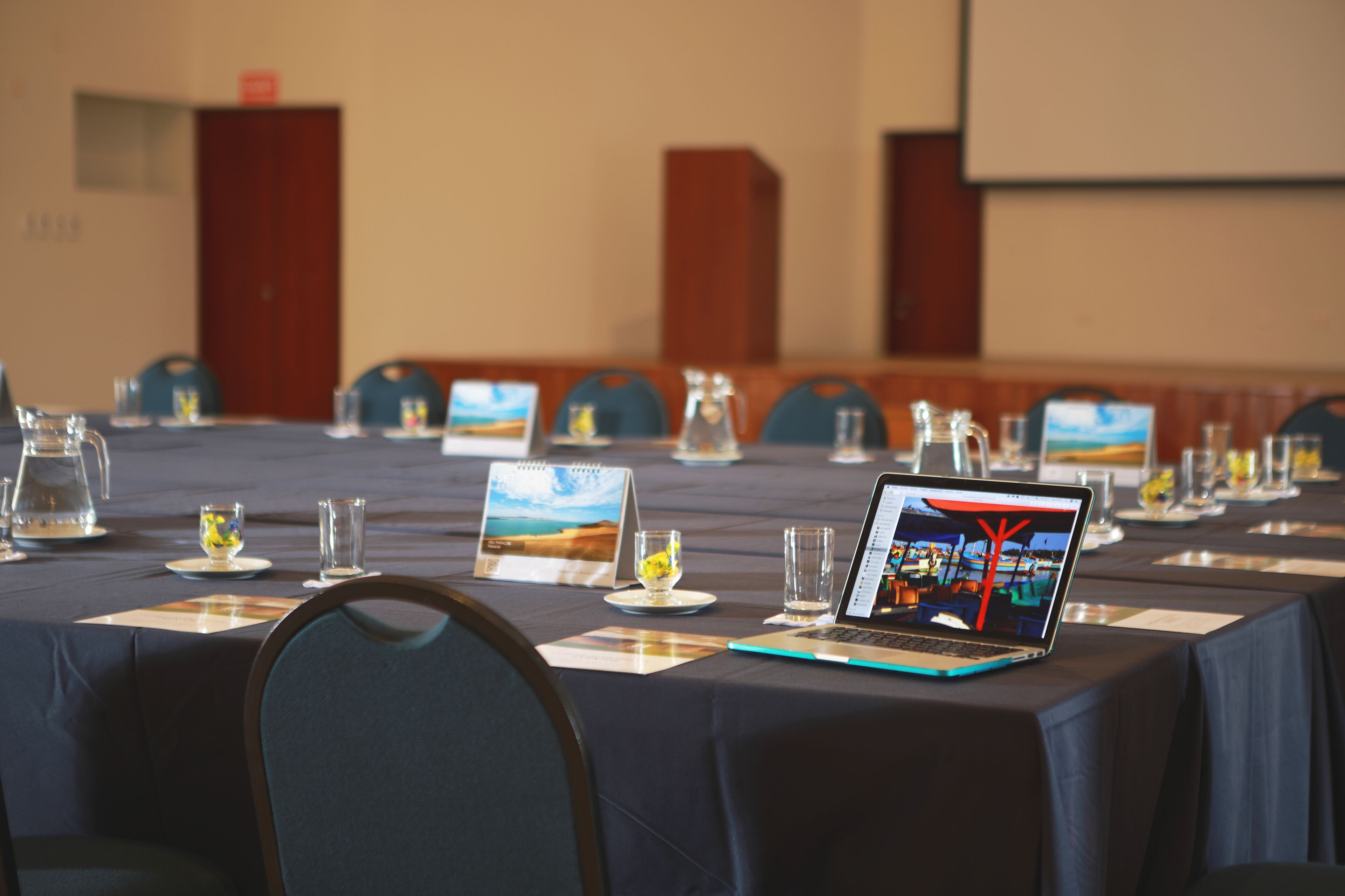A conference room with a long table set for a meeting, laptops, and nameplates.