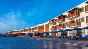 A hotel with multiple balconies, a pool area with sun loungers, and a clear blue sky. - Hotel San Agustín Paracas (Paracas)
