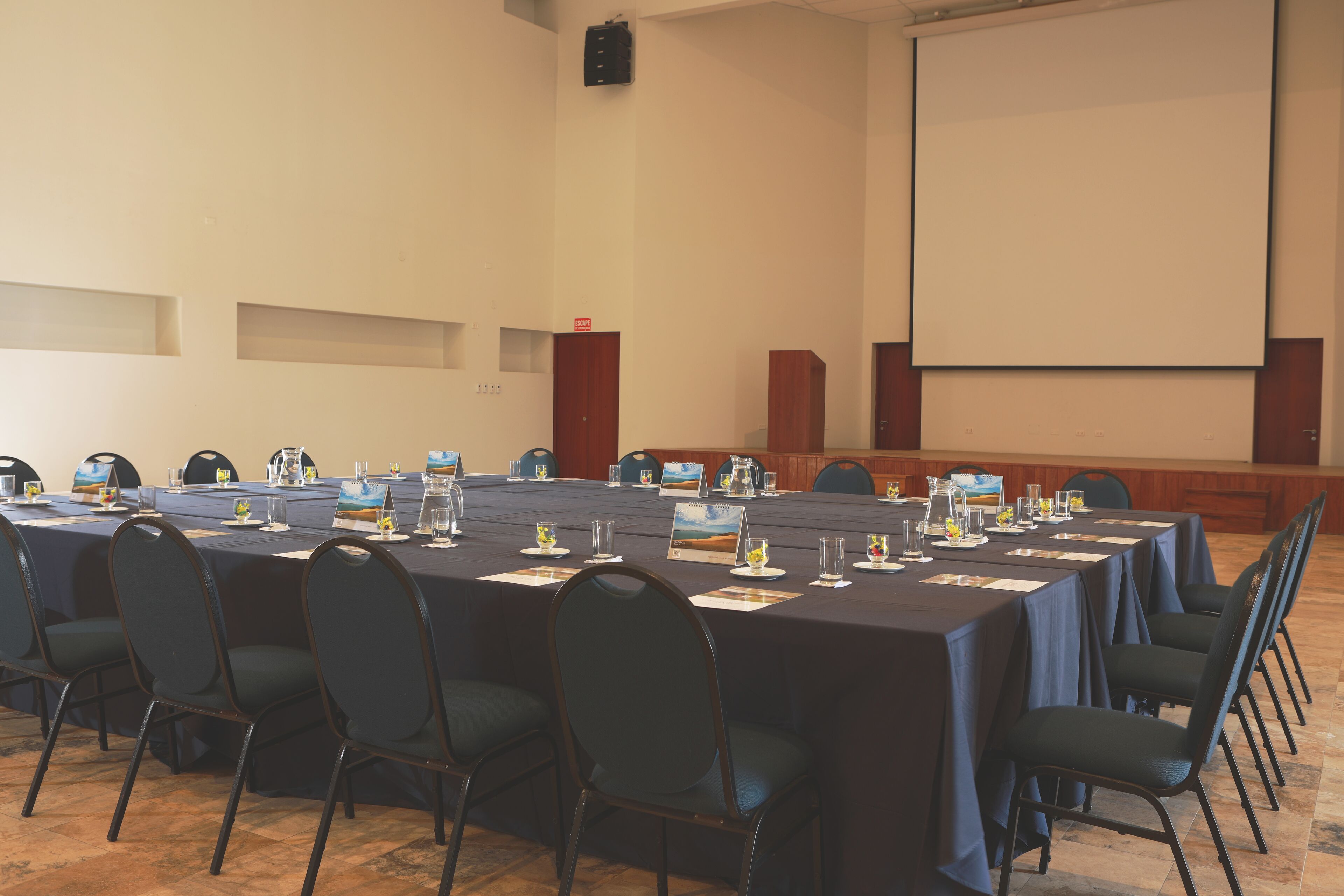 A conference room with a long table, chairs, and a projector screen.