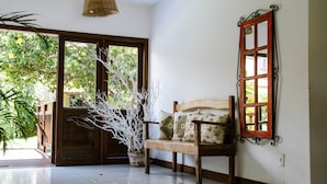 A room with a wooden bench, a potted plant, a woven ceiling light, and a red-framed window. - Bosque da Praia - ePipa Hotéis (Tibau do Sul)
