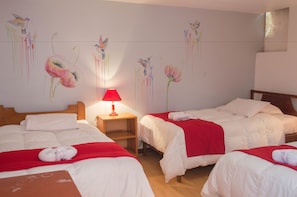 Una habitación de hotel con dos camas, una lámpara roja y decoración floral en las paredes.