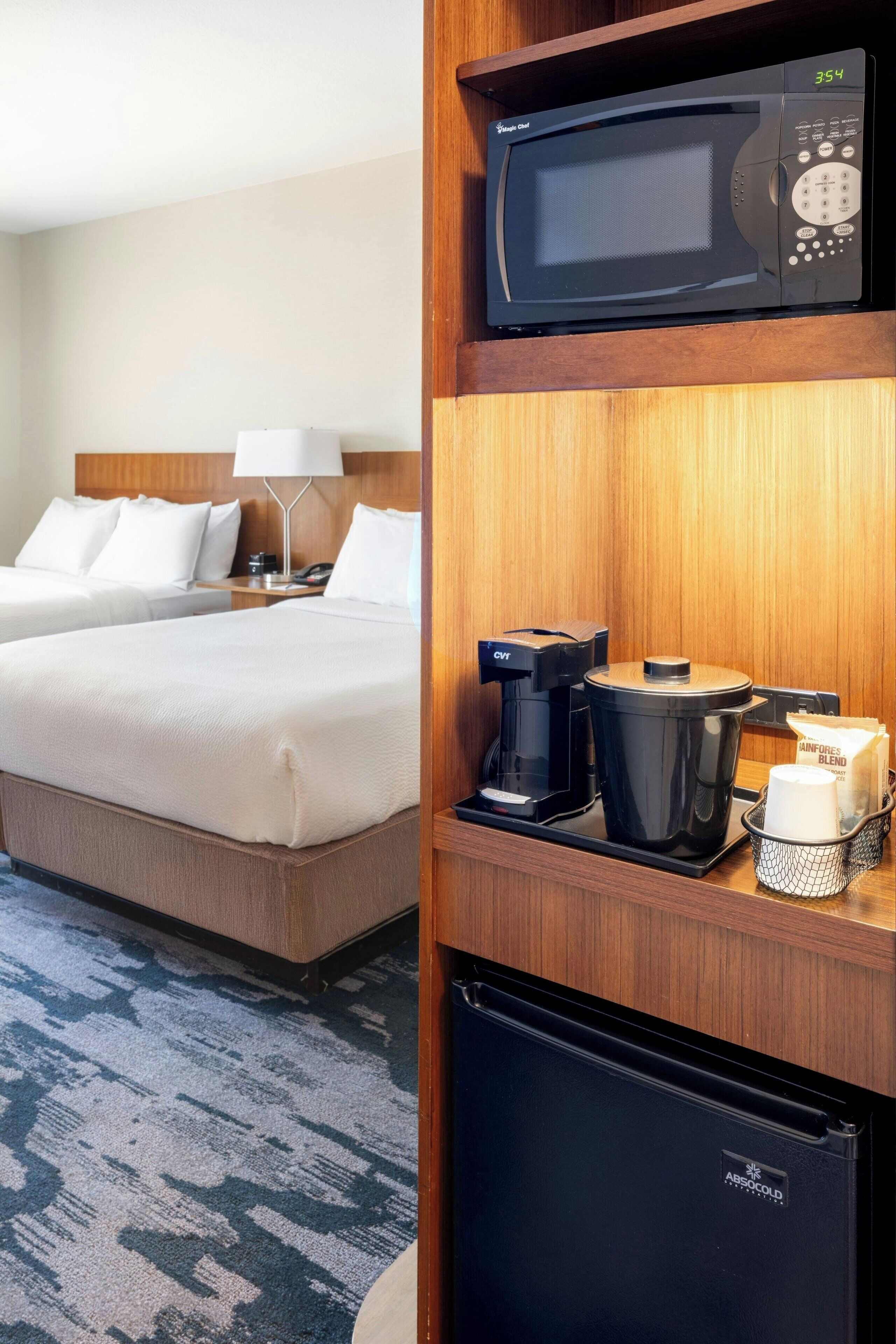 Een hotelkamer met een bed, koffiezetapparaat, magnetron en koelkast.