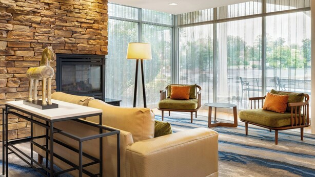 A modern living room with a stone wall, a fireplace, a sofa, two armchairs, and a coffee table.