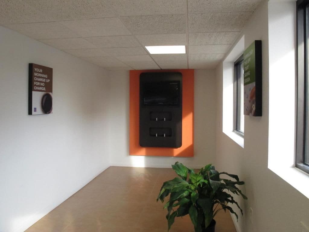 A hallway with a power outlet, a sign, and a potted plant.