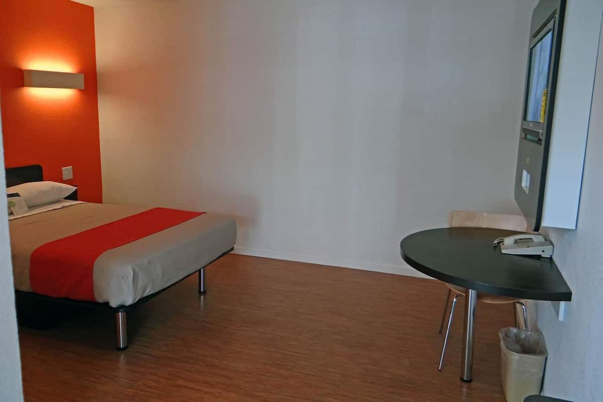 A hotel room with a bed, a small table, and a chair.