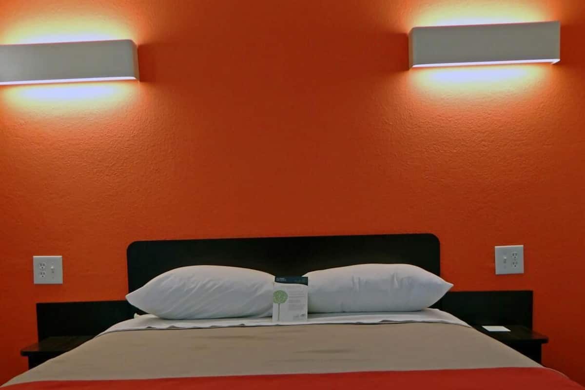 A bed with white bedding, two bedside tables, and two wall-mounted light fixtures.