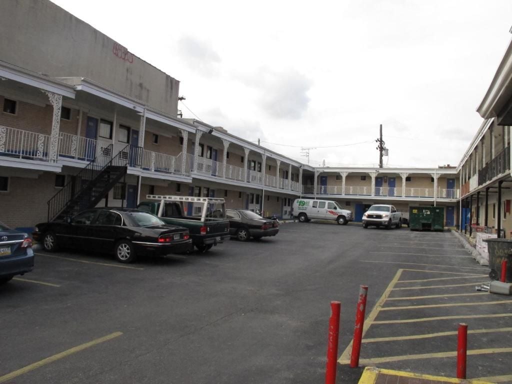 Un estacionamiento con varios automóviles y un edificio con balcones.