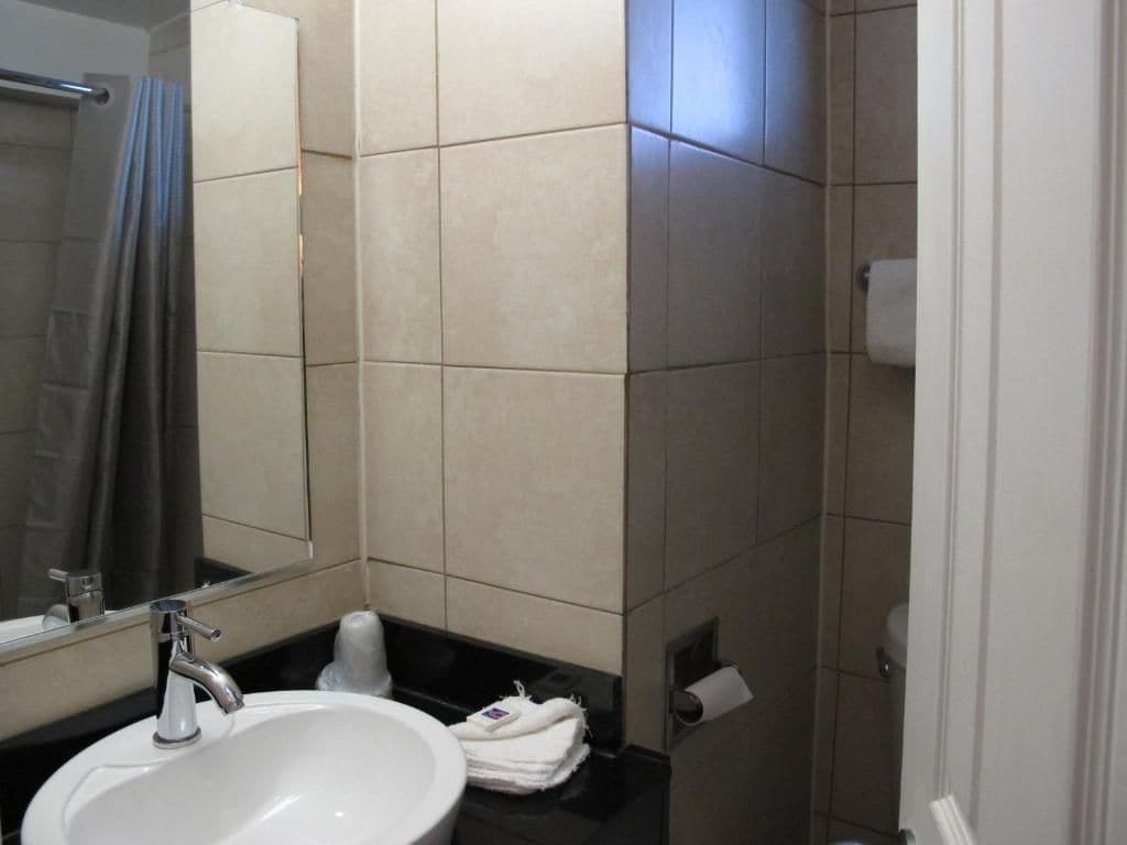 Een badkamer met een wastafel, spiegel en handdoekhouder.