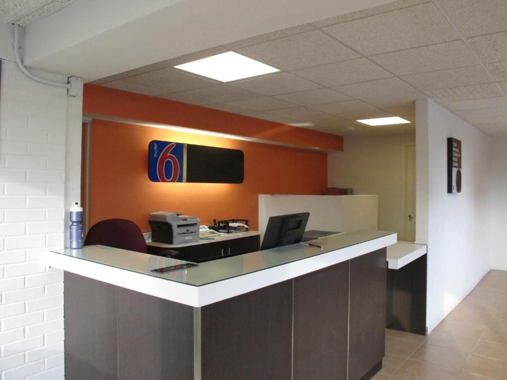 Mostrador de recepción con encimera de vidrio, una computadora e impresora. Hay un letrero con el número 6.
