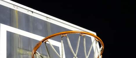 Un panier de basket avec un filet, placé devant un bâtiment doté de grandes fenêtres.