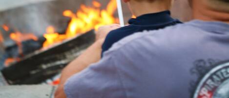 Een kind roost marshmallows boven een vuur.