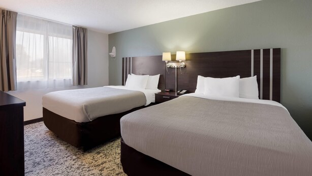 A hotel room with two beds, a desk, and a nightstand with lamps. - Quality Inn Hall of Fame (Canton)