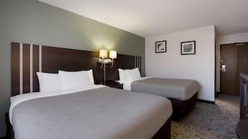 Habitació d'hotel amb dos llits, una tauleta de nit amb làmpades i una porta.