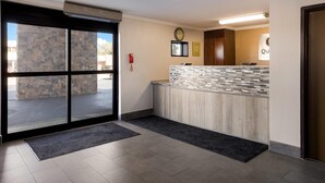A reception area with a stone wall, a clock, a fire alarm, and a reception desk with a tiled counter. - Quality Inn Hall of Fame (Canton)