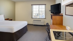 A hotel room with a bed, a desk with a computer, a television, and a window with blinds. - WoodSpring Suites Washington DC Andrews AFB (Suitland)