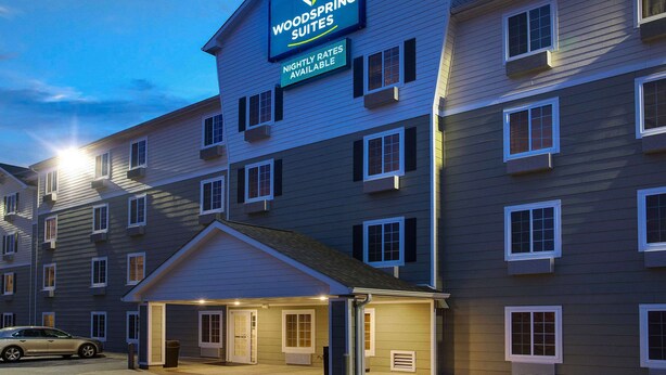 A multi-story hotel with a sign indicating "Woodspring Suites" and "Nightly Rates Available". - WoodSpring Suites Washington DC Andrews AFB (Suitland)