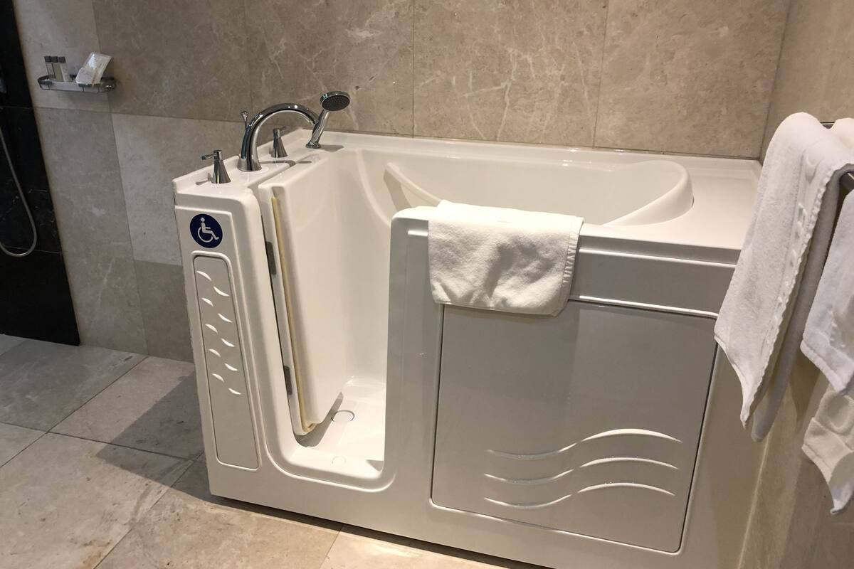 A modern bathroom with a walk-in shower, grab bars, and a towel rack.