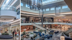 Um grande centro comercial com vários andares, um átrio central, escadas rolantes e áreas de estar.