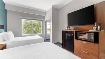 Habitación de hotel con dos camas, televisión, microondas y refrigerador.