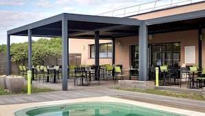 An outdoor pool area with a covered patio and seating.