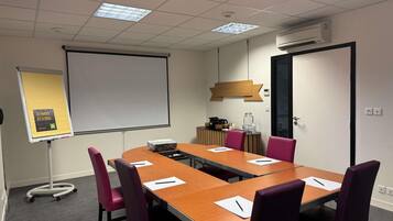 A conference room with a long table, chairs, a projector, and a screen.