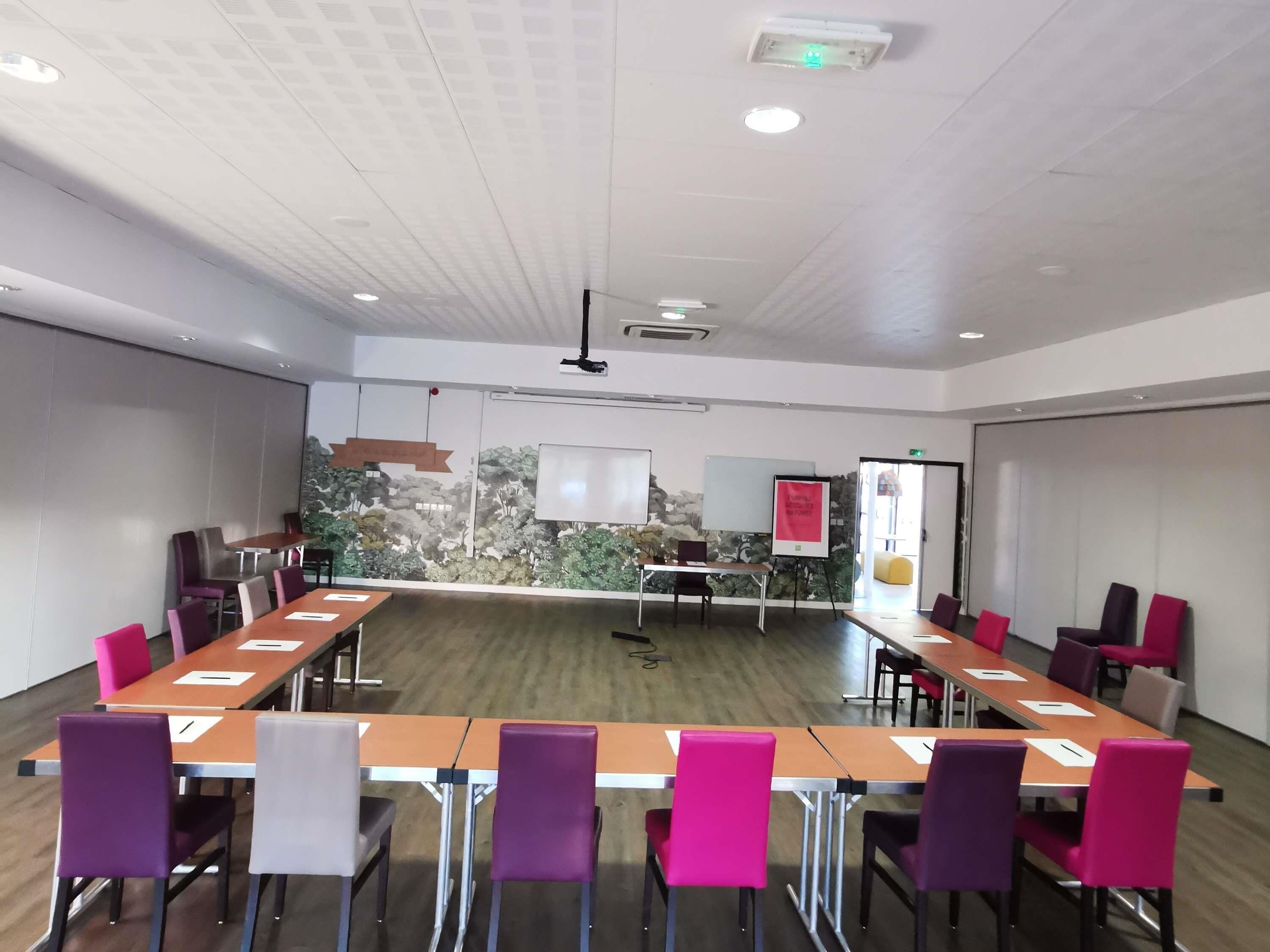 A conference room with a long table, chairs, a whiteboard, and a projector.