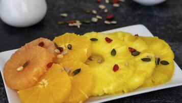 Un plato de frutas cortadas con semillas y frutas deshidratadas sobre una superficie oscura.