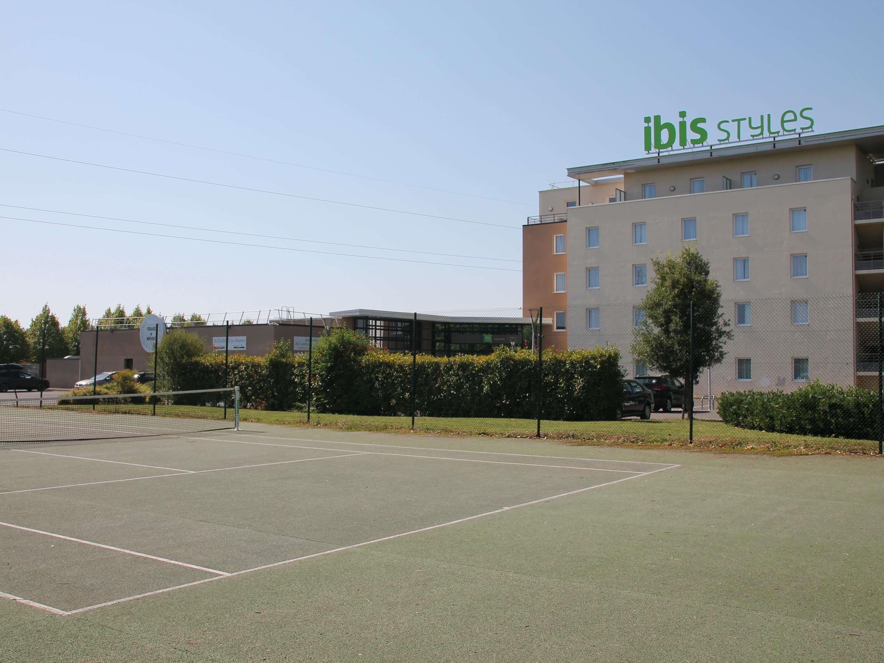 Una cancha de tenis con una red, rodeada de una valla y follaje.