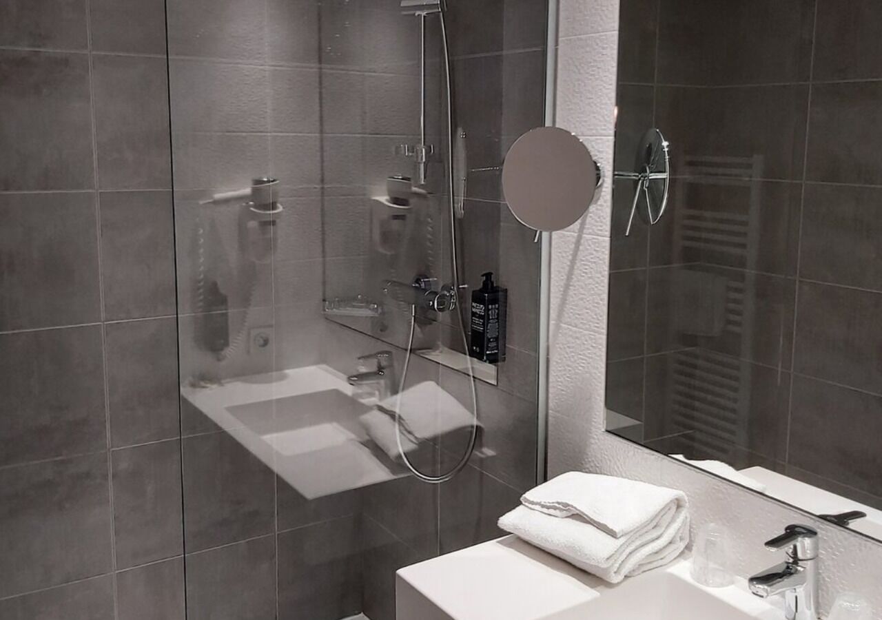 A modern bathroom with a glass-enclosed shower, a white sink, and a mirror.