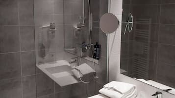 A modern bathroom with a glass-enclosed shower, a white sink, and a mirror.
