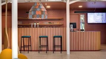 Un coin bar avec un comptoir à rayures, trois tabourets et une lampe suspendue.