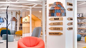A modern interior with a red bean bag chair, a wooden sign with directional arrows, and a unique ceiling decoration.