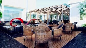 A covered outdoor seating area with wicker chairs and a red circular sculpture. - Days Hotel Dawn Fuzhou (Fuzhou)