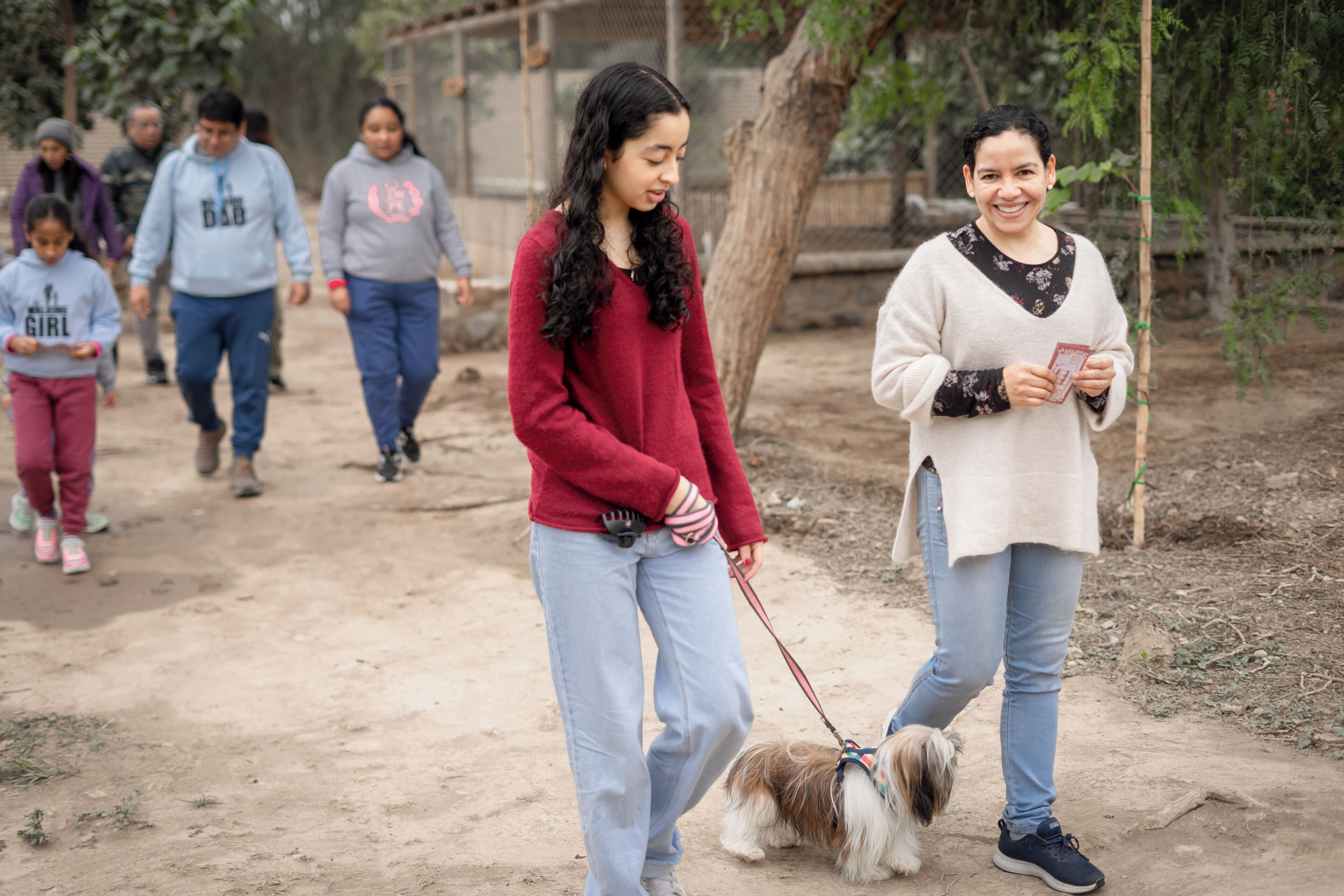 A group of people walking on a dirt path with trees in the background.