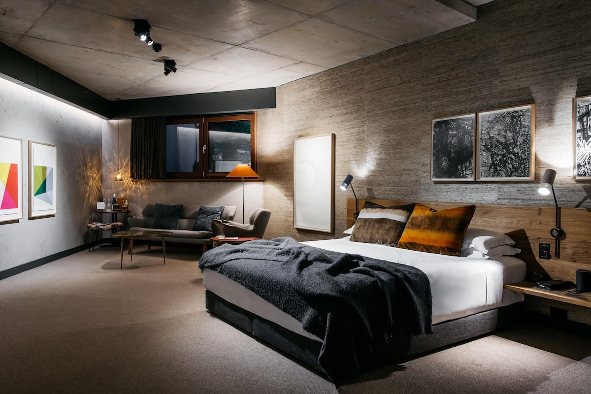 Un dormitorio moderno con una cama grande, un escritorio, una silla y obras de arte en las paredes.