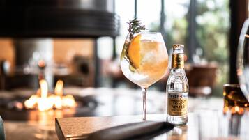 Een glas tonic met een citroenpartje en een takje rozemarijn, samen met een fles met de tekst 'Fever-Tree Premium Indian Tonic Water'.