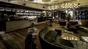 A modern bar area with a wooden floor, bar counter, and seating area with sofas and tables. - Ovolo Canberra, a Wyndham Hotel (Canberra)