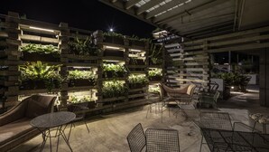 An outdoor patio area with a modern design, featuring a tiered planter wall with greenery, comfortable seating, and a staircase leading to an upper level. - Ovolo Canberra, a Wyndham Hotel (Canberra)
