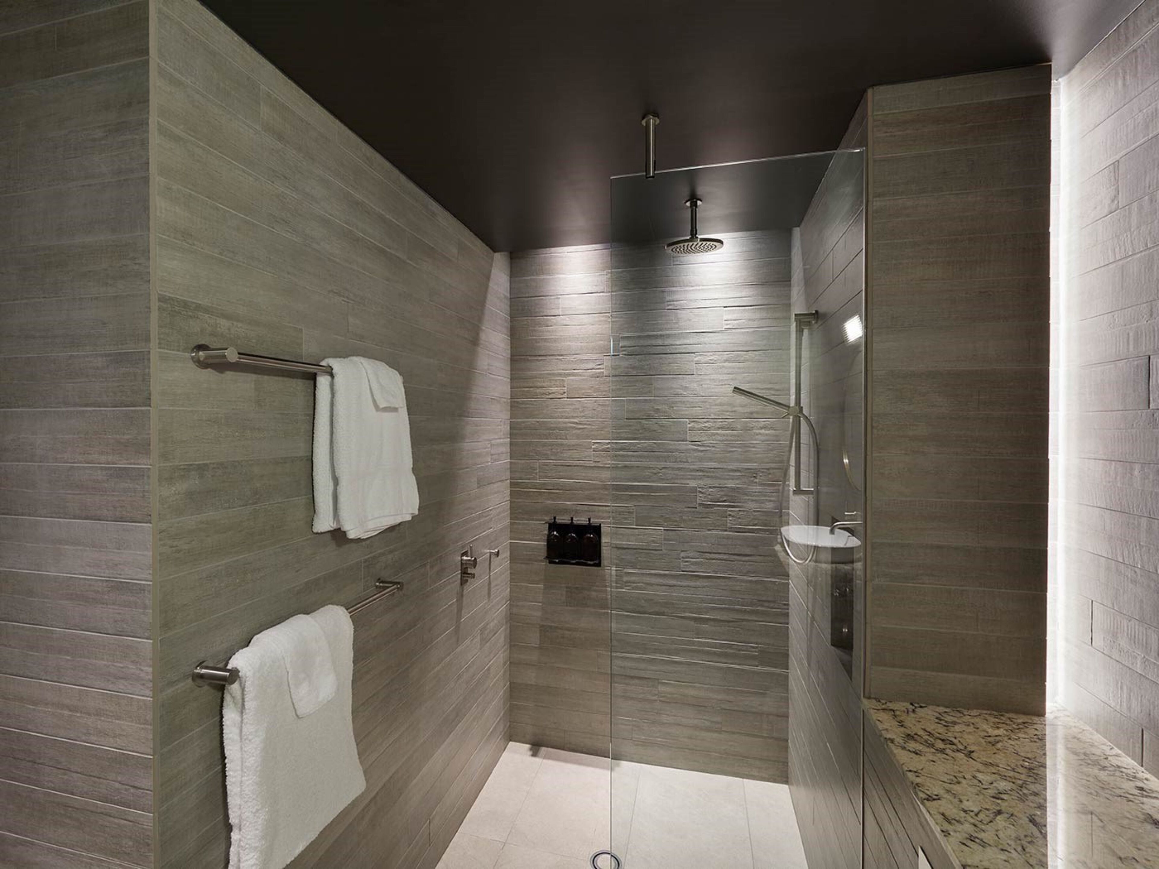 A modern shower with a glass enclosure, a towel rack, and a wall-mounted towel dispenser.